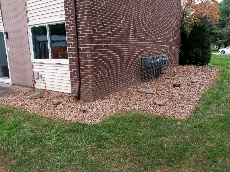 landscaping after example, showing the removal of the large bushes, replaced by mulch and rocks.